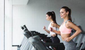 Sporty women running on treadmill, doing cardio workout in gym